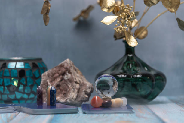 A serene tarot card reading space with assorted healing crystals, a candle lantern, and a geode on a weathered wooden surface