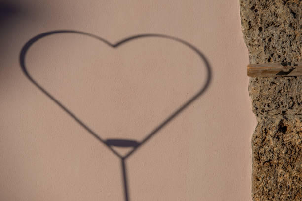 Metal heart reflecting the shadow against the wall