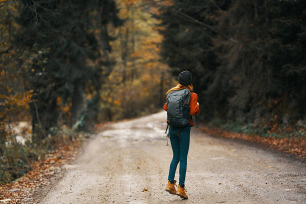 istock happy traveler with backpack walks on the road in autumn forest 2115696401