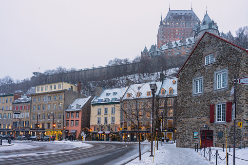 Quebec city Quebec streets with vintage European style store fronts at the famous shopping street Norte Dame while snowing and famous hotel behind the walled city on a hill. Winter wonderland look and feel.