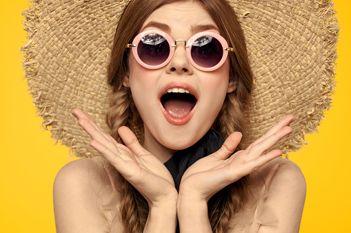 Romantic woman in hat having fun on a yellow background and sunglasses black ribbon model portrait. High quality photo