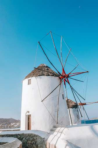 Landscape view of traditional old white windmills in Mikonos town (Chora), Mykonos island, Cyclades, Greece at sunset time with clear sunny sky.