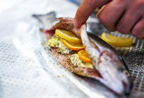 Preparing trouts with lemons, butter and dill. Close up.