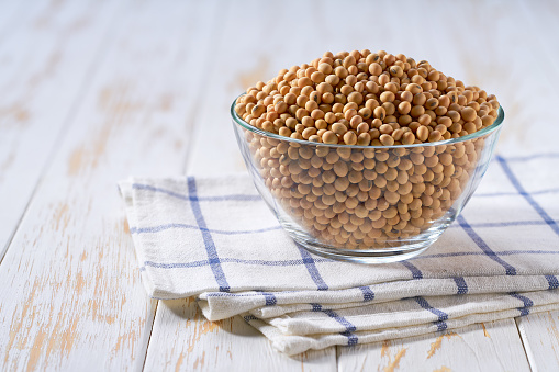Organic soybeans in a clear glass bowl on a light table, selective focus.