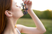 charming woman with a vine of grapes outdoors in a meadow
