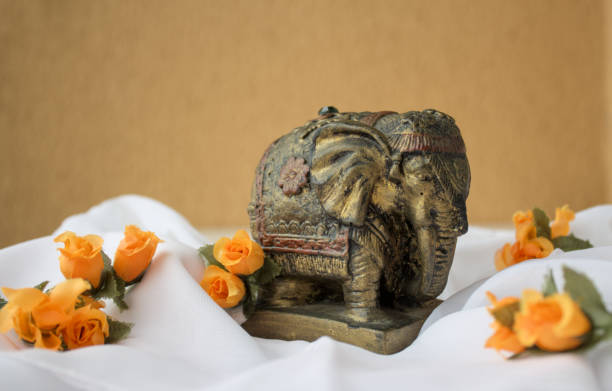 istock Ancient Indian elephant statuette on white fabric and flowers 2115825382