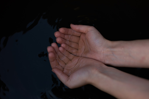 female hands on a dark background transparent water river nature fresh air. High quality photo