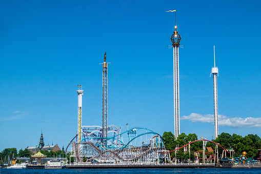 Sweden's fun filled amusement park Gröna Lund in city of Stockholm on a clear blue sunny day looking at rollercoaster from the waterfront
