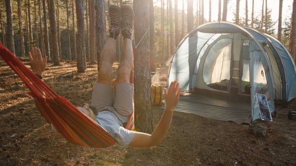 istock Man swinging in hammock in tent camping in nature at sunset. 2115847607