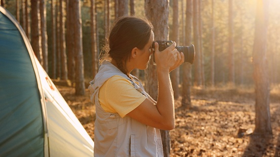 Woman on adventure trip in pine forest with her camera.