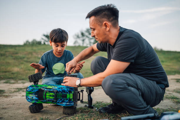 istock Son enjoying time with dad while fixing toy car in nature. 2115849371