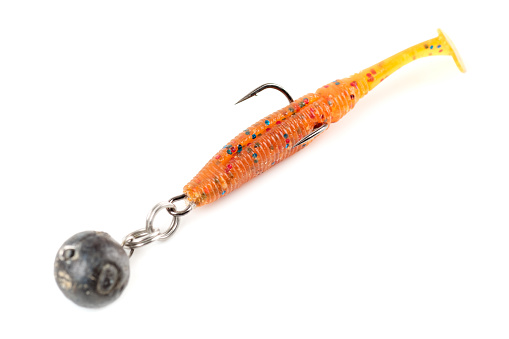 Orange fishing lure, plastic shad fish, with double hook and lead sinker, isolated on white background