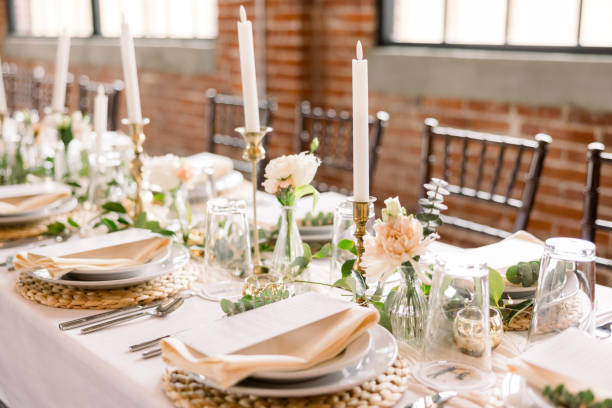 istock Elegant wedding reception table decor with beautiful place settings with the dinner menu on top of a napkin, flowers in dainty vases, and tall candlesticks to add a romantic feel. 2115852737