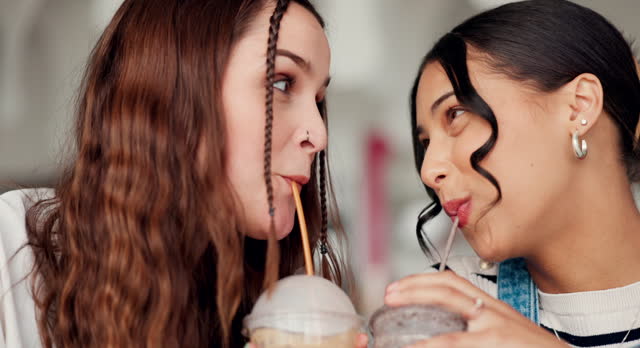 Happy, girl friends and milkshake in a restaurant with healthy drink and smile in cafe. Silly, young women and female bonding in a coffee shop or diner with a funny joke and drinking with smoothie
