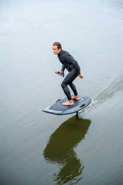 Hydrofoil rider gliding over the water with his board in one of the canals of the Ria de Aveiro in Portugal on a cloudy day.