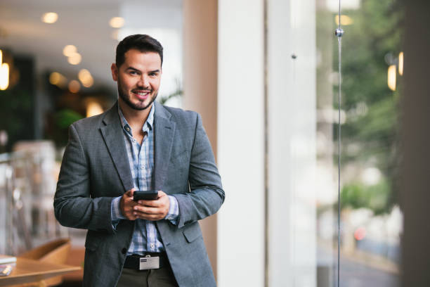 istock Young man, standing and using the cell phone inside of a house 2115913978