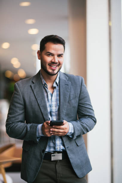 istock Young man, standing and using the cell phone inside of a house 2115913980