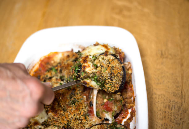 Hand Spooning Out Eggplant Parmigiana