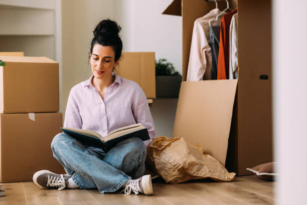 istock Young Woman Relaxing with Book During Moving Day 2115959754