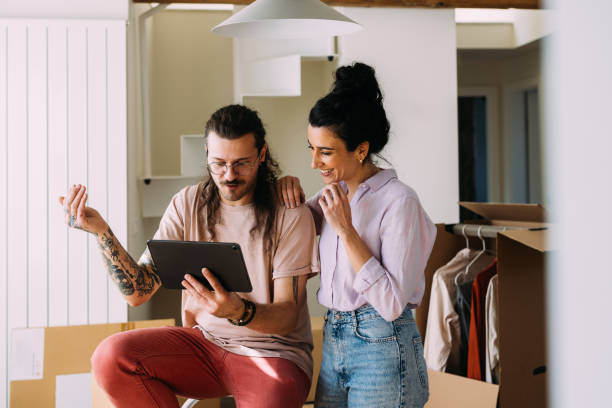 istock Young Couple Enjoying Digital Tablet in New Home Setting 2115960303