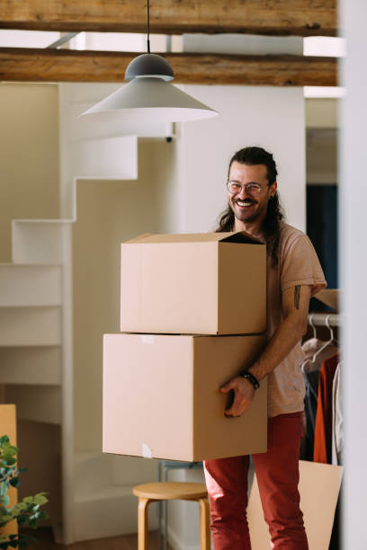 istock Cheerful Man Moving New Home Carrying Cardboard Boxes Indoors 2115960888