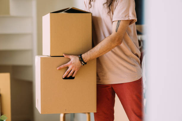 istock Man Carrying Cardboard Boxes During Moving Day Indoors 2115960894