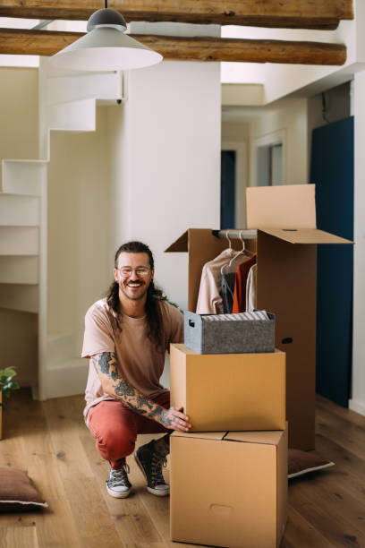 istock Smiling Man with Tattoos Sitting with Moving Boxes in New Home 2115960904
