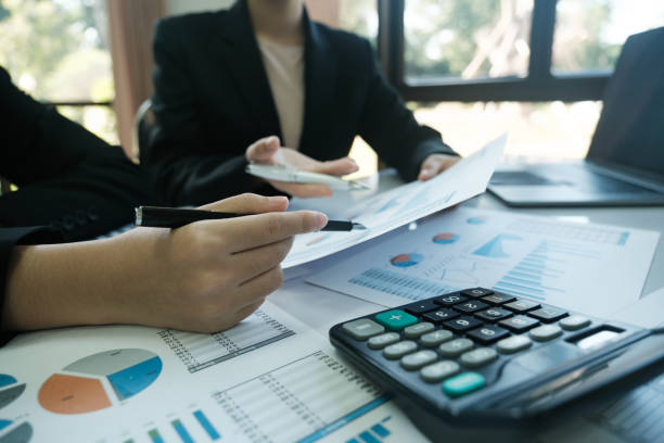 istock Two people are sitting at a table with a calculator and a stack of papers 2115962034