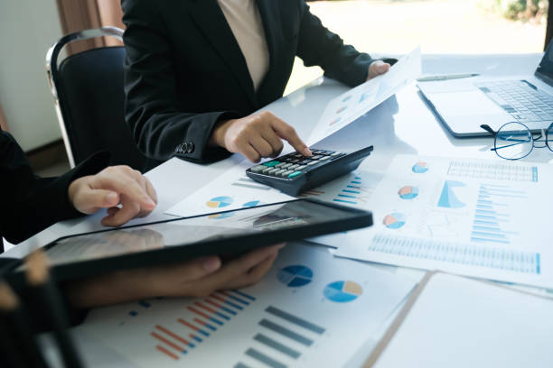 istock Three people are sitting at a table with a calculator and a tablet 2115962166