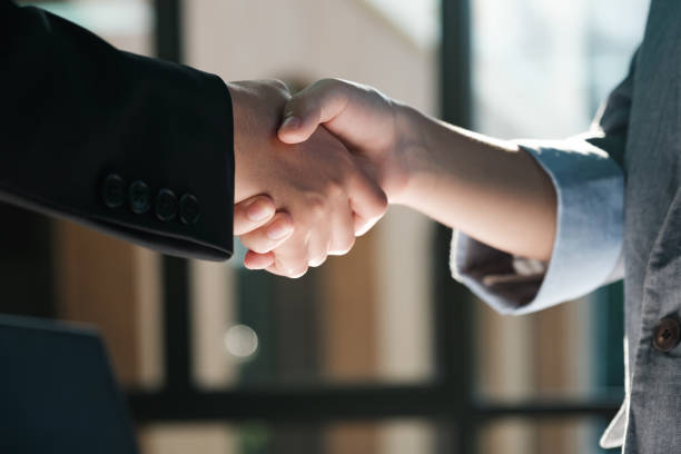 istock Two people shaking hands in a business setting 2115963096