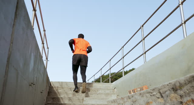 Back of man, fitness and running on steps outdoor for cardio exercise, workout and sports training. Runner, urban performance and action on stairs for energy, wellness challenge and strong endurance