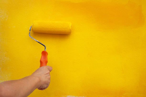 istock Painting a wall with yellow paint 2116066209