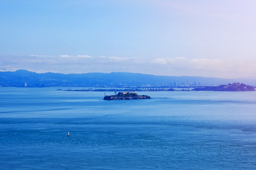 Scenic ocean view of Alcatraz island and San Francisco city from Golden Gate Bridge in sunlight landscape photo. California landmark.