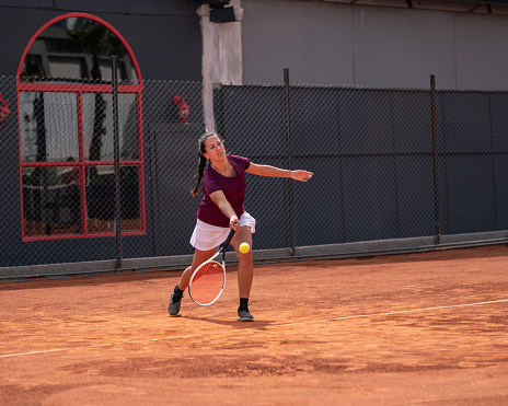 women tennis player is shooting forehand on clay court horizontal sport still