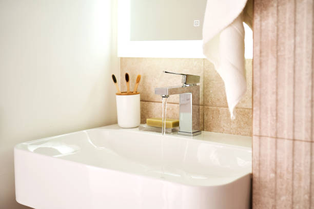 istock Bathroom sink with toothbrushes and running water. 2116123177