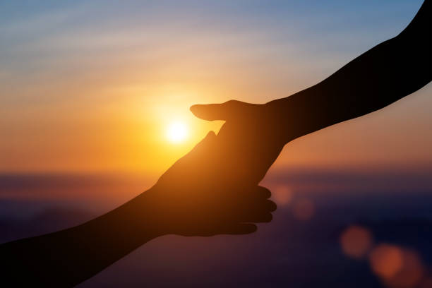 istock Silhouette of giving a helping hand, hope and support each other over sunset background. 2116154766