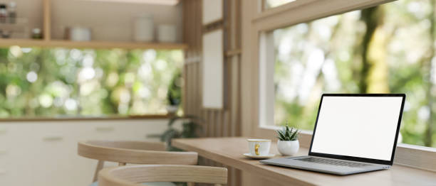 istock A laptop computer mockup on a wooden dining table against the window in a neutral modern kitchen. 2116221026
