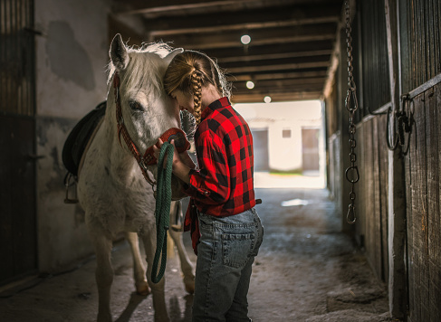 Cropped shot of a girl preparing to ride her pony on a farm