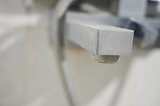 Close-up of a faucet in lime scale with shallow depth of field. Bath faucet with lime scale.