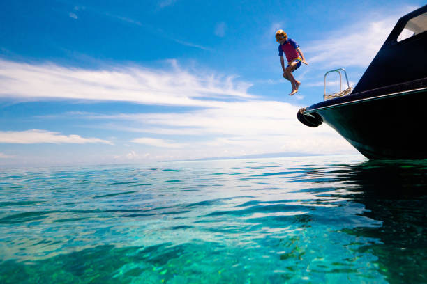 Kids jump into sea. Yacht vacation with child on exotic tropical island with crystal clear water. Beach and swim fun. Sailing and cruise with children. Summer holiday on boat. Little boy swimming.