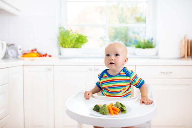 istock Baby eating vegetables in kitchen. Healthy food. 2116349965