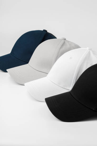 istock Four Baseball Caps in Black, White, Grey, and Blue Arranged on a Plain Background 2116395870