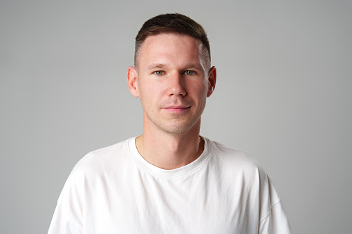 Portrait of a young handsome male in casual clothes on gray background close up