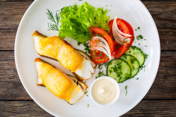 istock Fried halibut fillet and fresh vegetables on wooden table 2116409845