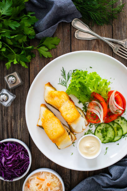 istock Fried halibut fillet and fresh vegetables on wooden table 2116410350