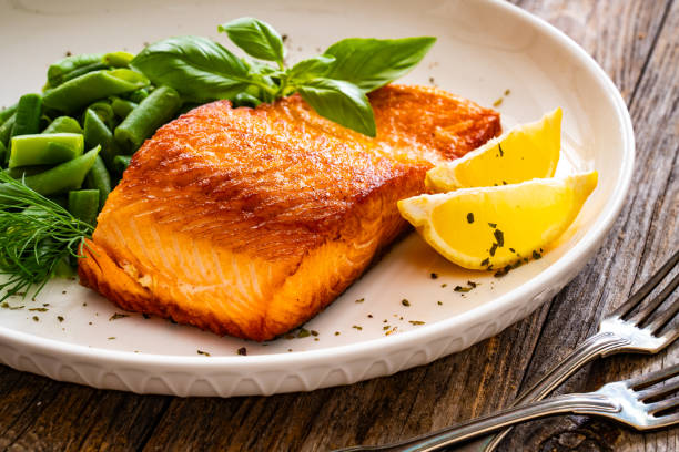 istock Seared salmon steak with boiled green bean on wooden table 2116414984