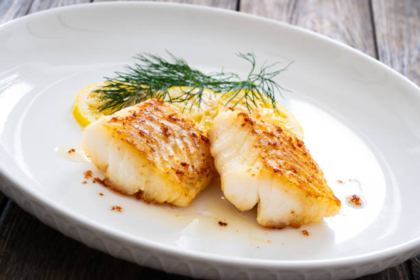 istock Fried codfish loin, lemon slices and dill on wooden table 2116416551