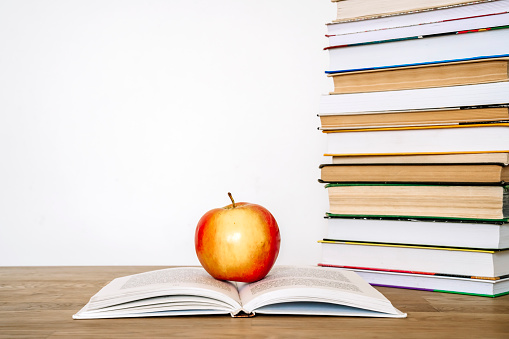 Books and an apple on a desk in a school or university classroom. Education, study concept background. High quality photo