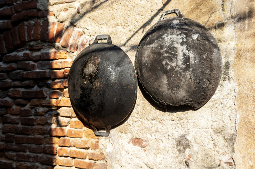 Old ancient dishes on cracked wall. Rusty cauldrons