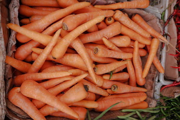 Pile of fresh carrot vegetables in a basket, at a traditional market.